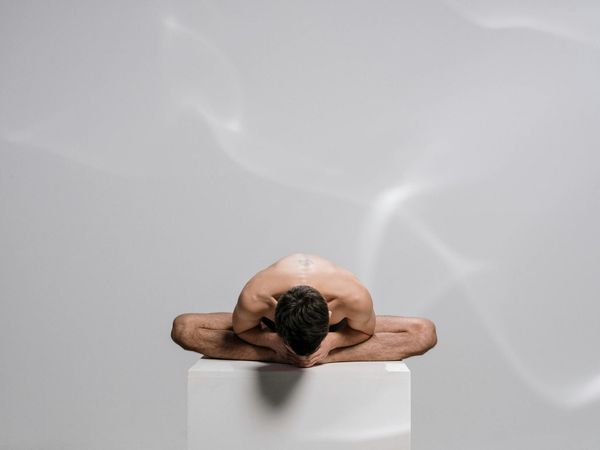 Man achieving a balanced yoga pose in a minimal studio
